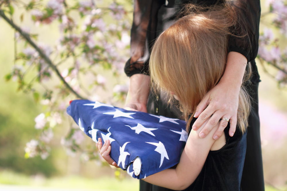 Daughter,Holding,A,Parent's,Folded,American,Flag,With,A,Woman's